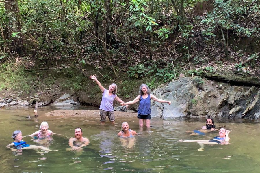 Travelers swimming in a clear forest river during a Trinidad and Tobago nature experience