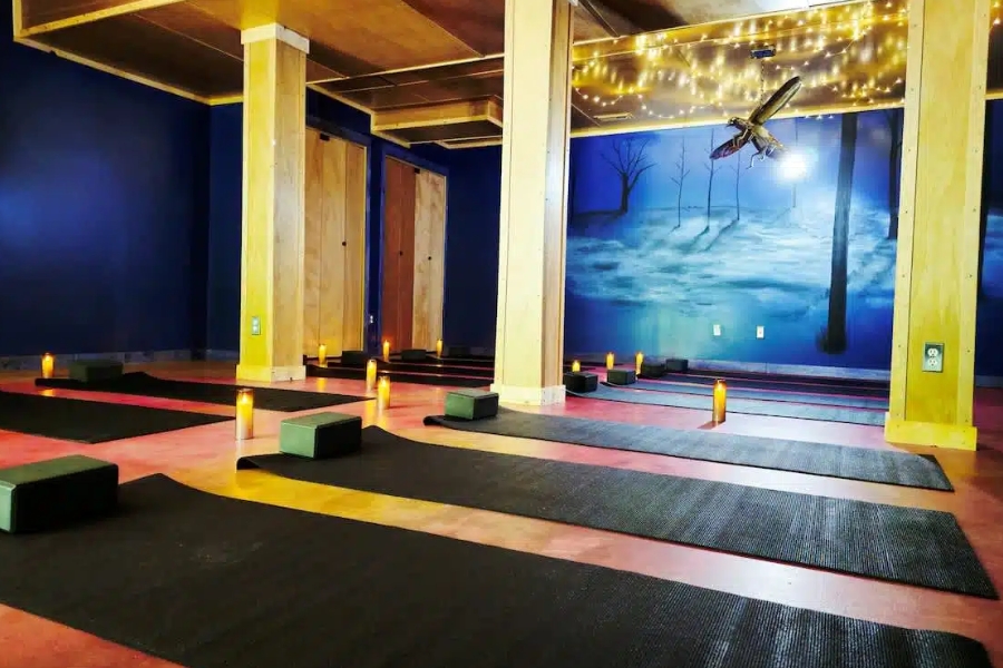 Indoor yoga and wellness room at Raven’s Retreat Hocking Hills with mats, candles, and a forest mural.