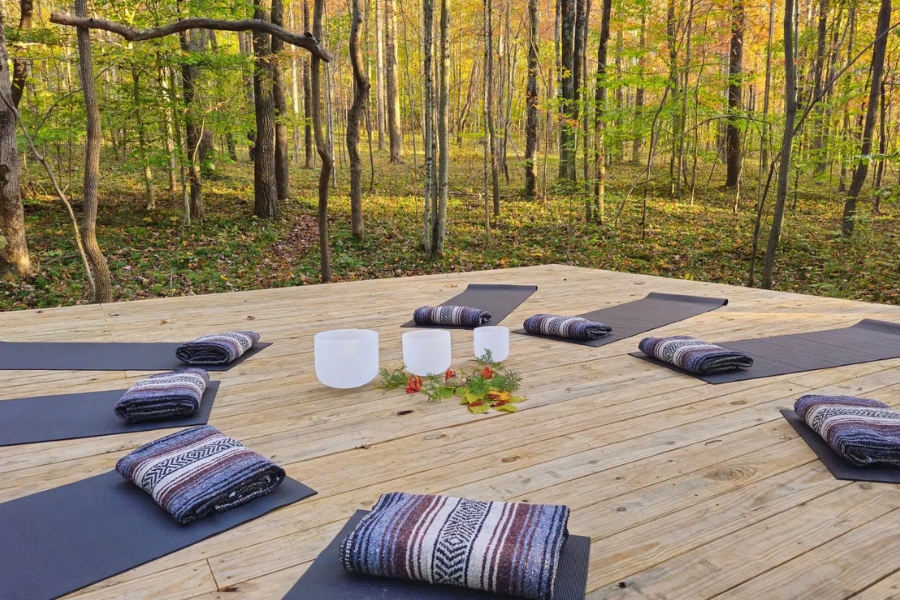 Outdoor yoga mats on a wooden forest deck at a vegan wellness retreat in Ohio.