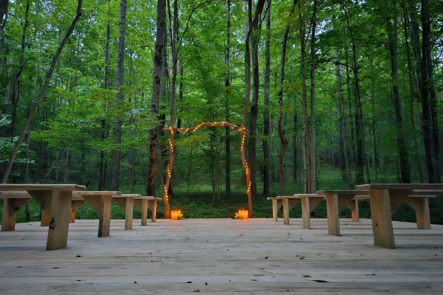 Forest platform with wooden benches and soft lights at Raven’s Retreat Hocking Hills.