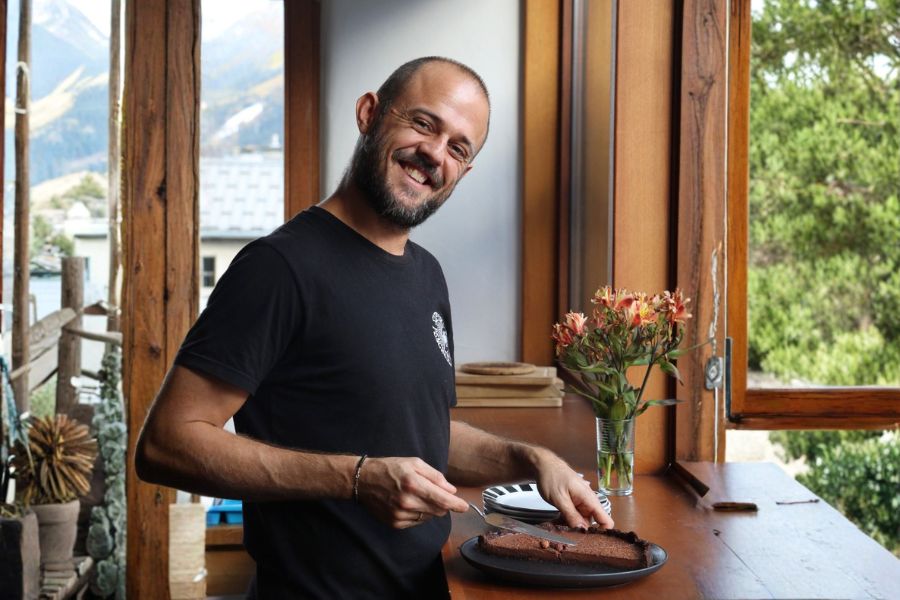 Vegan chef Ben Riddle smiling beside a plant-based cake.