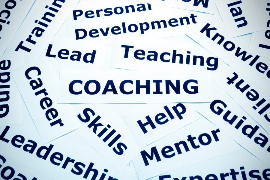 Coaching and personal development words printed on overlapping paper cards.