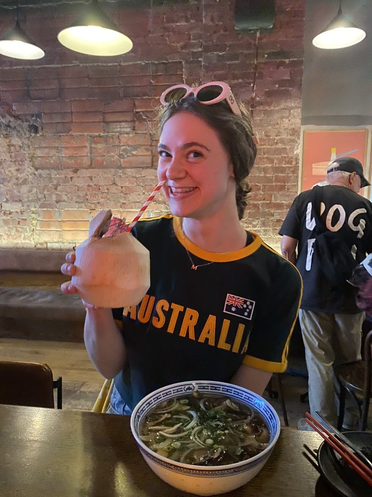 Kiara enjoying a meal and coconut drink while exploring Australia
