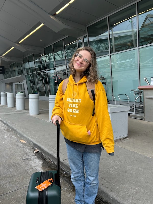 Solo traveler Kiara with suitcase outside an airport before an Australia and New Zealand adventure