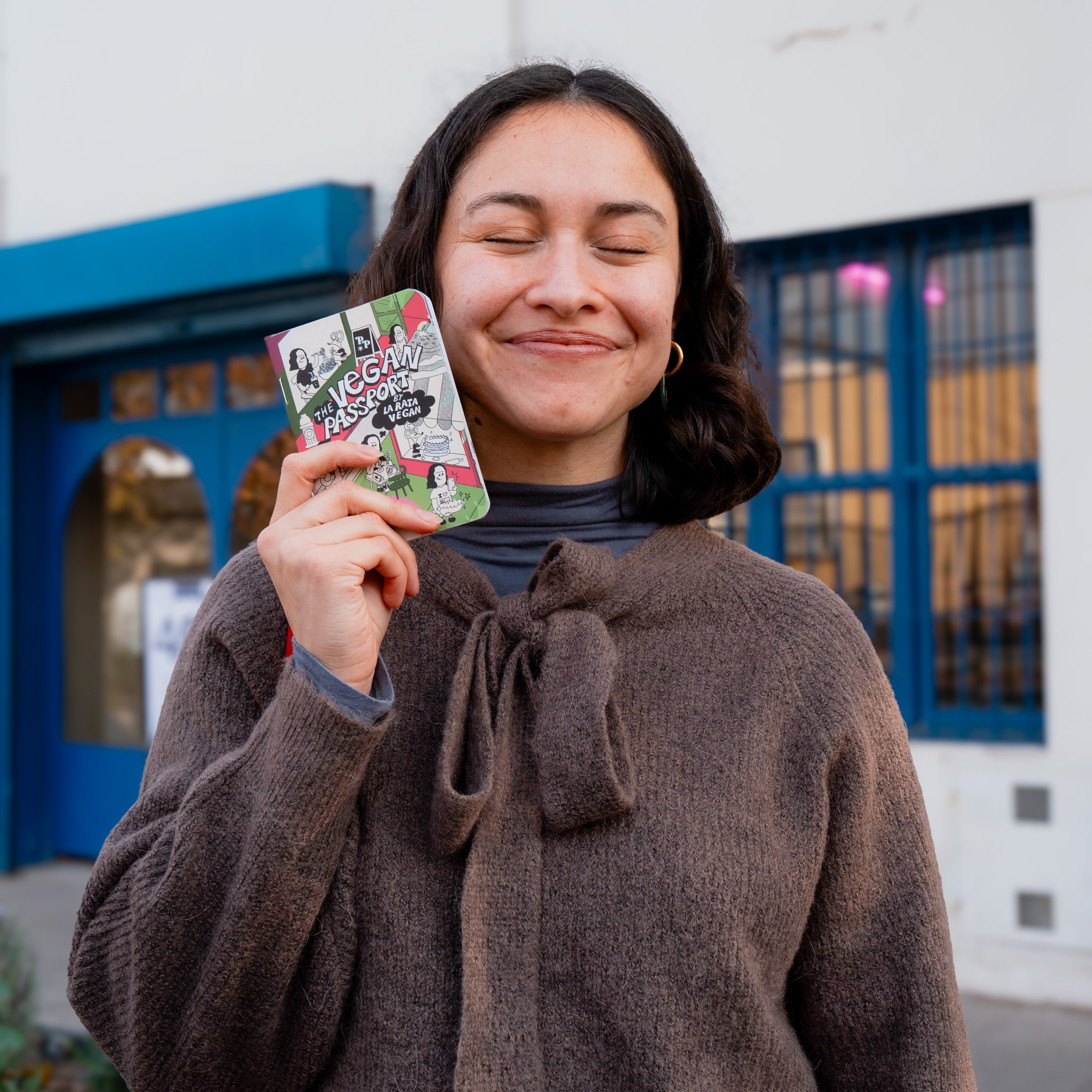 Natalia Rojas smiling and holding The Vegan Passport by La Rata Vegan