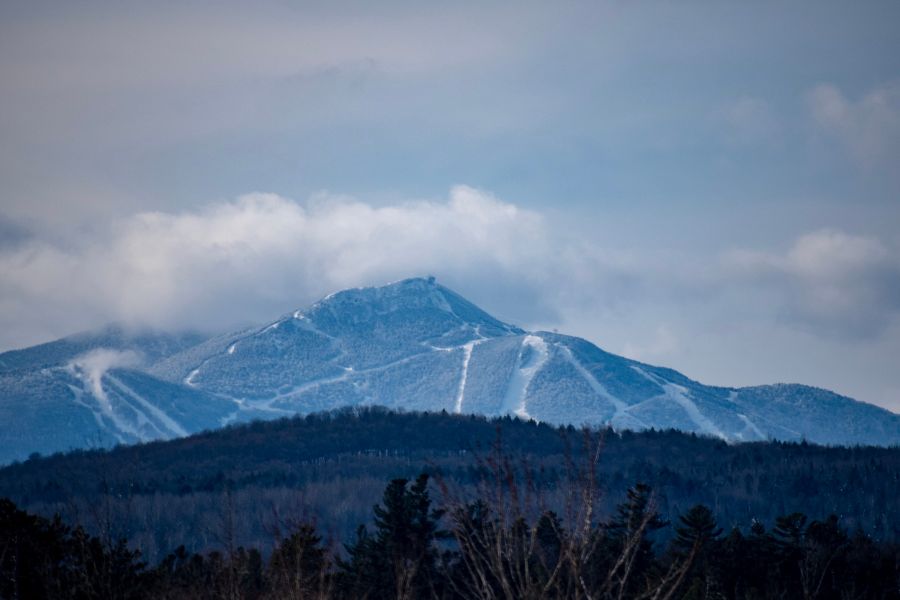 Snow-covered ski slopes on Jay Peak in Vermont, with forested hills and low clouds
