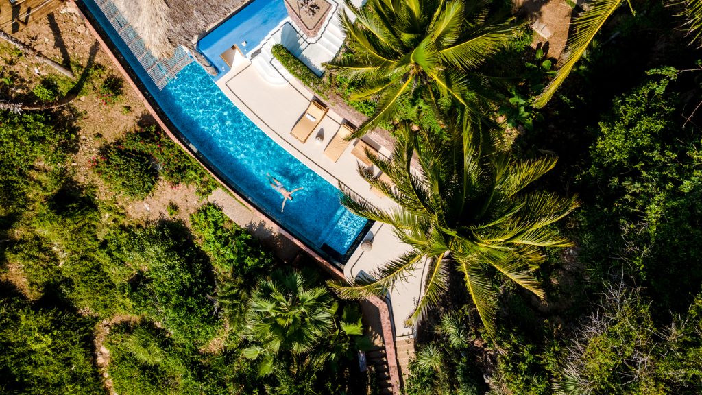 Aerial view of the Nido de Amor pool surrounded by palm trees in Careyes
