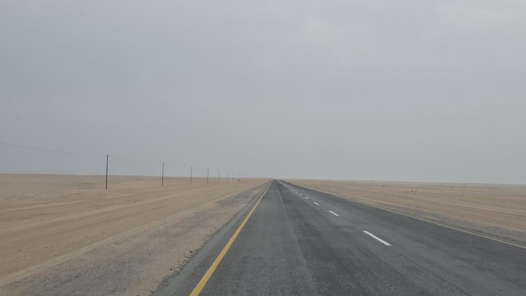 Desert road disappearing into coastal fog on the way to Swakopmund